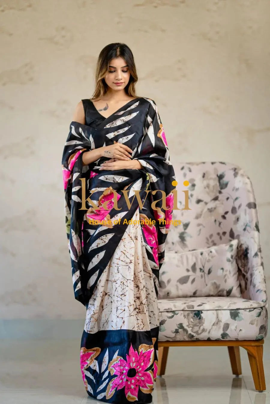 Kawaii black and white batik saree with pink floral patterns draped on a woman standing by a floral armchair